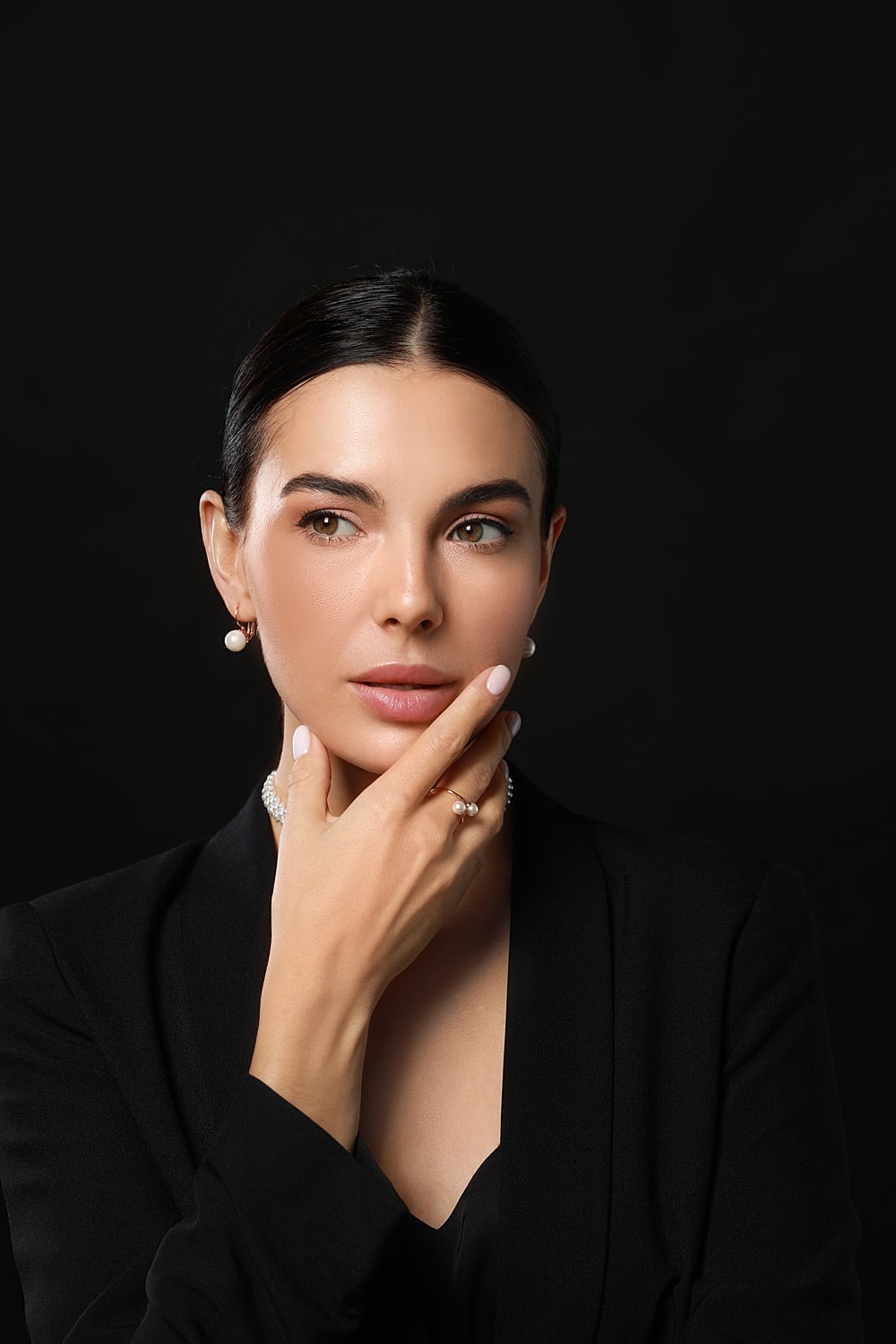 Elegant woman in black attire, thoughtful expression.