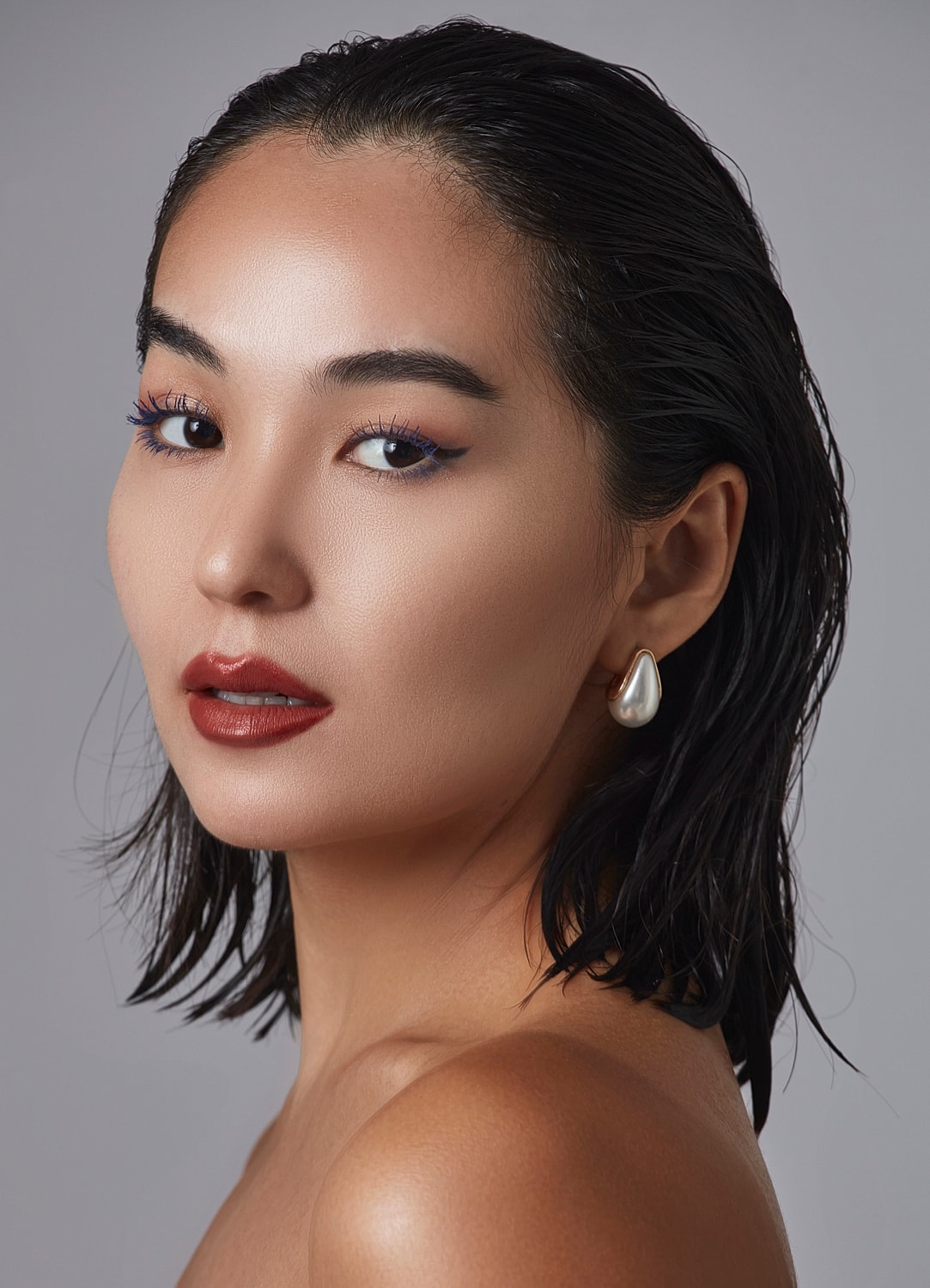 Model with bold makeup and wet hair.